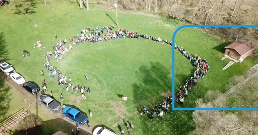 A group of people gather in a circle on some grass.