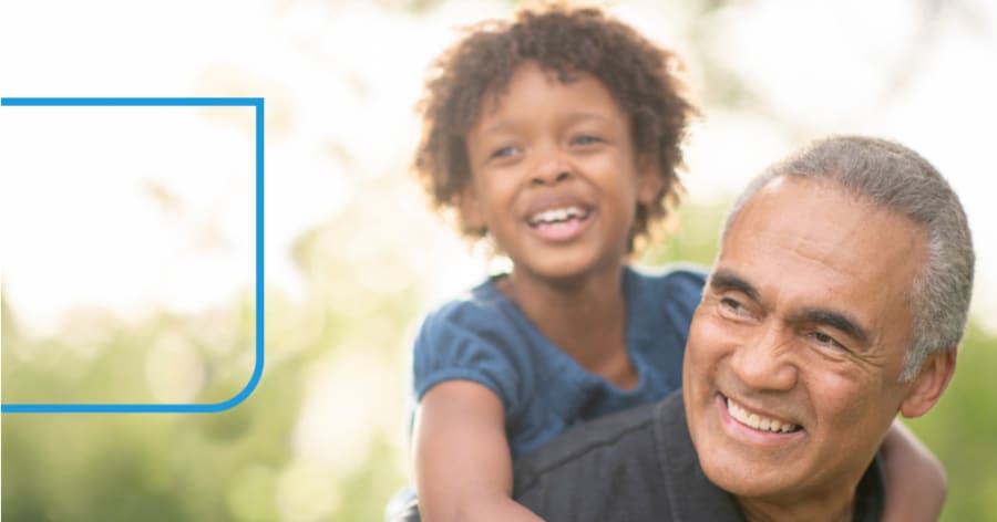 A young boy rides on a man's back. They are both smiling.