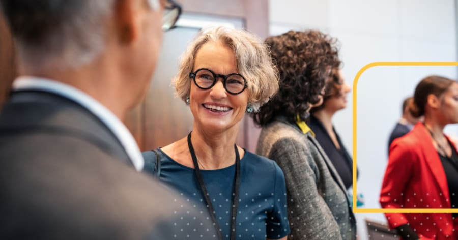 An older woman with round glasses is smiling.