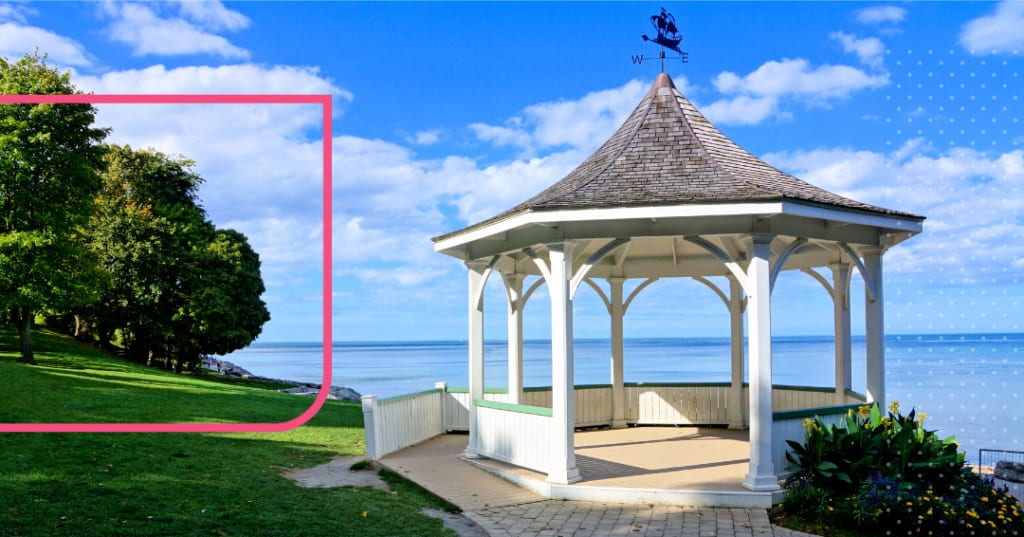 Gazebo beside a lake with trees to one side.